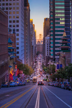 繁忙的市中心街道，纜車和摩天大樓在夕陽下熠熠生輝。 — 天際線 壁紙