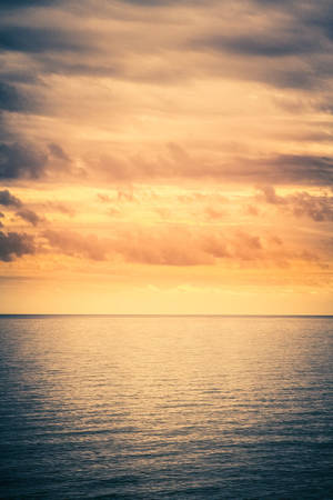 寧靜的海平線，閃耀著夕陽色彩和柔和的雲朵。 — 海洋 壁紙