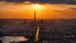 夕陽落在密集的城市天際線上，金色光芒照亮摩天大樓和主要高速公路。 — 唐人街 壁紙
