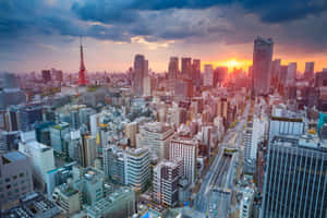 日落時分的東京城市景觀，東京塔和摩天大樓沐浴在橙色光芒中。 — MacBook Air M3 壁紙