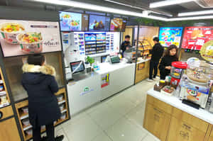 顧客在現代韓國便利商店使用自助服務機。 — 7-ELEVEN 壁紙