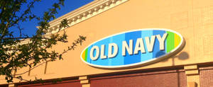 陽光明媚的日子裡，Old Navy 商店招牌呈現彩虹色，前景有樹枝。 — Off white 標誌 壁紙