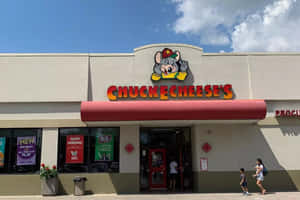 Chuck E Cheese's遊戲機餐廳，卡通老鼠吉祥物和進入的人們。 — 查克芝士 壁紙