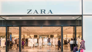 Zara服裝店，透過玻璃門可見購物者和人體模型。 — Zara 壁紙