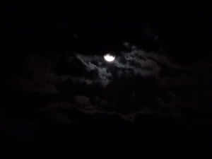 彎月在黑暗夜空中飄動的雲層後發光。 — 月落 壁紙