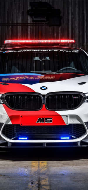 車庫內一輛紅藍白色塗裝的寶馬M5安全車的前視圖。 — Galaxy A07 壁紙