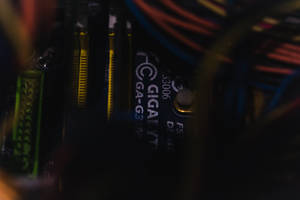 電腦主機板的特寫，帶有彩色電纜和發光的綠色組件。 — 電路板 壁紙