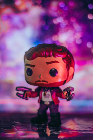 星爵Funko Pop公仔在反射表面上手持發光武器，置身於彩色燈光下。 — 傳說對決英雄 壁紙