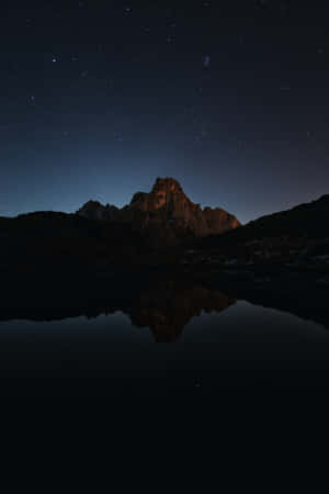 山峰和星空倒映在夜晚的平靜湖面上。 — POCO Pad 壁紙
