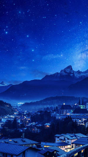 山城在星空夜空下，窗戶發光，山峰積雪。 — 山景 壁紙
