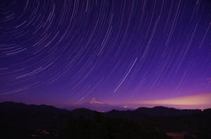 星軌在深紫色夜空下，於富士山上空盤旋。 — 酷 壁紙