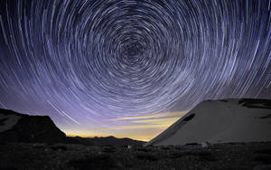 星軌在積雪的山峰上空盤旋。 — 星星 壁紙