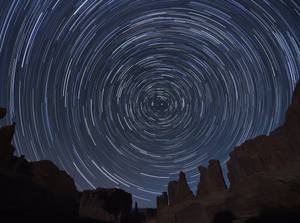 星軌在深藍色夜空下盤旋於沙漠岩石地貌之上。 — 星星 壁紙