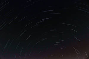 星軌在長時間曝光的照片中彎曲穿過黑暗的夜空。 — 酷黑 壁紙