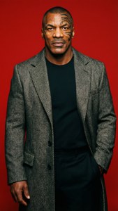 Mike Tyson 穿著灰色外套，背景為紅色，帶有面部紋身。 — 麥克·泰森 壁紙