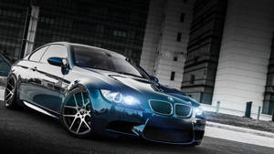 時尚的藍色BMW M3轎跑車夜間停在城市街道上，頭燈發光。