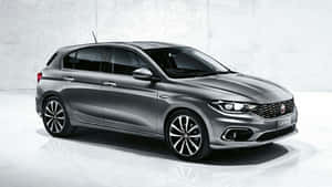 銀色 Fiat Tipo 掀背車在攝影棚中，配有反光地板和混凝土牆。 — 飛雅特 壁紙
