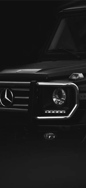 黑色 Mercedes G-Wagen 前格柵和頭燈在昏暗攝影棚燈光下的特寫。 — Mercedes Benz C300 壁紙
