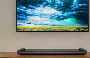 電視下方的現代 soundbar，顯示田野上空的暴風雨天空 — 電視 壁紙