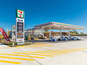7-Eleven加油站，有Mobil油泵和黃色條紋路面，天空湛藍。 — 4:3 壁紙