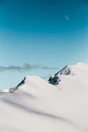 明亮藍天下白雪覆蓋的山脊，可見一彎新月。 — 寒冷 壁紙