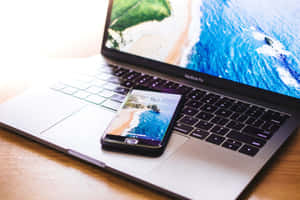 智慧型手機和筆記型電腦在木桌上顯示相同的海灘桌布。 — MacBook Air 壁紙