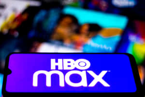 手機特寫，顯示HBO Max應用程式標誌，背後有模糊的串流內容。 — HBO 壁紙