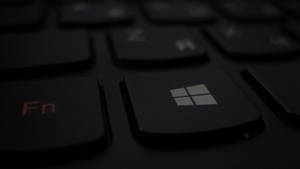 黑色鍵盤的特寫，帶有發光橙色 Fn 鍵和亮起的 Windows 標誌鍵。