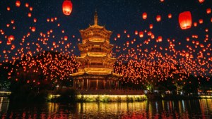 一幅令人驚嘆的景象，紅色發光燈籠在繁星點綴的天空中升起，映襯著一座寶塔與河流。
