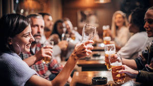 一群朋友在舒適的酒吧裡用啤酒乾杯。 — 麥迪遜·比爾 壁紙