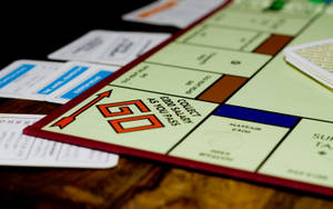 Monopoly 遊戲板，有 GO 格和卡牌在木質表面。 — 地產大亨 壁紙