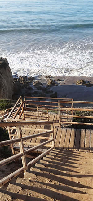 通往岩石海灘的木樓梯，海浪拍打。 — 海灘 壁紙