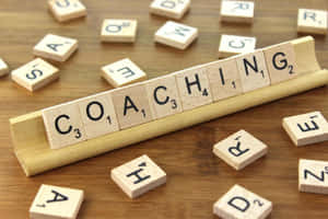 木桌上拼出 coaching 的 Scrabble 字母牌。 — 教練 壁紙