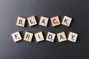 在深灰色背景上用木製 Scrabble 字母牌拼出 Black Friday。 — 純黑 壁紙