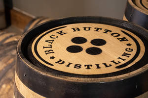 帶有 Black Button Distilling 標誌的威士忌酒桶特寫。 — 棕色 壁紙