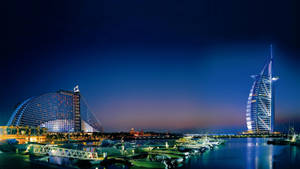 杜拜天際線夜景， featuring 帆船酒店及亞特蘭蒂斯酒店，碼頭有船隻。 — 城市風景 壁紙