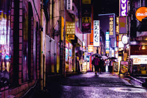 行人撐傘走過夜晚東京下雨且霓虹燈照亮的小巷。 — 東京 壁紙