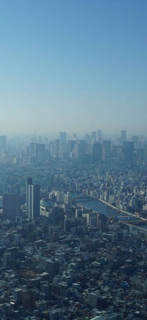 東京城市景觀，河流和摩天大樓在清澈藍天下。 — Galaxy A18 壁紙