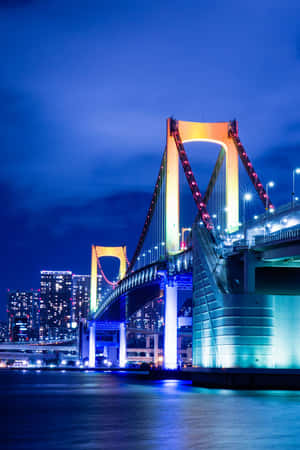 夜晚的東京彩虹橋，城市燈光倒映在水面上。 — 2:3 壁紙