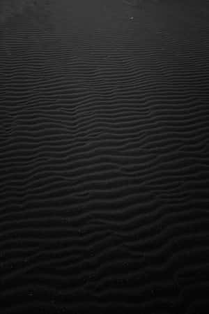 深色波紋沙粒，帶有細微紋理和散落的斑點。 — 4K iPhone 壁紙