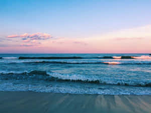 日落時分，海浪輕輕拍打沙灘，天空呈現粉紅和藍色。 — 海景 壁紙