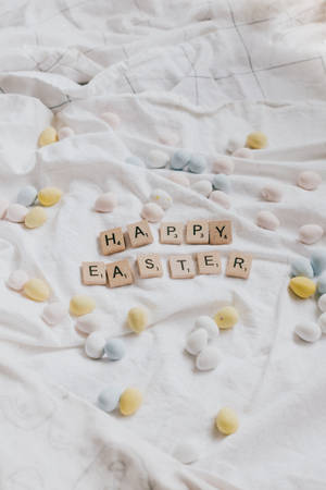 用Scrabble字母牌拼出的Happy Easter，被粉彩蛋環繞，置於白色布料上。 — 可愛 壁紙