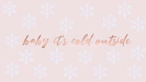 粉紅色桌布，帶有白色雪花和玫瑰金色文字，寫著 baby it's cold outside。 — 玫瑰金 iPhone 壁紙