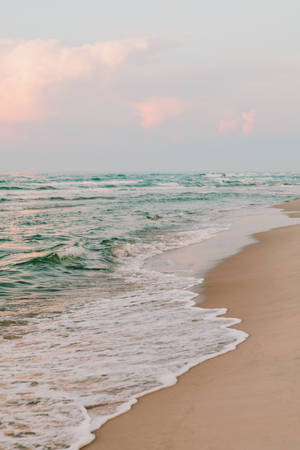 海洋波浪在日落時輕輕沖刷沙灘，天空呈現粉彩色。 — 海灘 壁紙