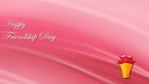 在粉紅色緞面背景上帶有禮物盒的 Happy Friendship Day 問候 — 友誼日 壁紙