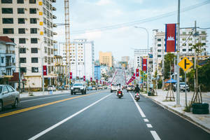 柬埔寨的城市街道，有摩托車、汽車和國旗，在明亮的天空下。