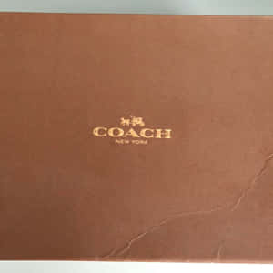 棕色 Coach New York 品牌盒子，帶有金色標誌和可見摺痕。 — 教練 壁紙