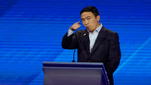 身穿西裝的男子在藍色舞台的講台上發表尖銳的演講。
