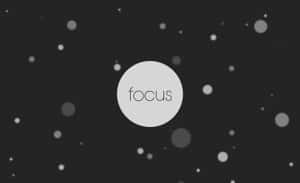 一個圓圈中的「focus」字樣居中，周圍環繞著漂浮的小點，背景為深色。 — 焦點 壁紙