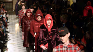 模特兒穿著紅色連帽衫和格子襯衫走在時裝伸展台上。 — Vetements 壁紙
